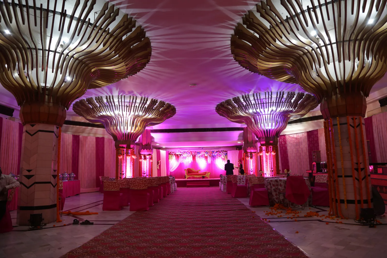 Decorated banquet hall with a central aisle and floral stage