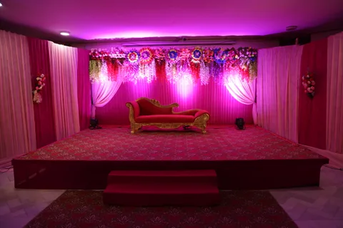 A floral stage with draped curtains and an ornate red sofa