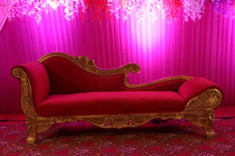 An ornate red-and-gold sofa beneath hanging flowers